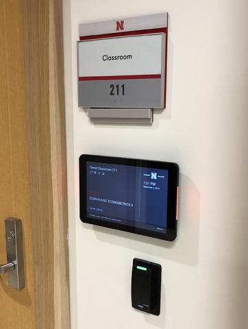 Wide view of room schedule sign including physical room sign and door